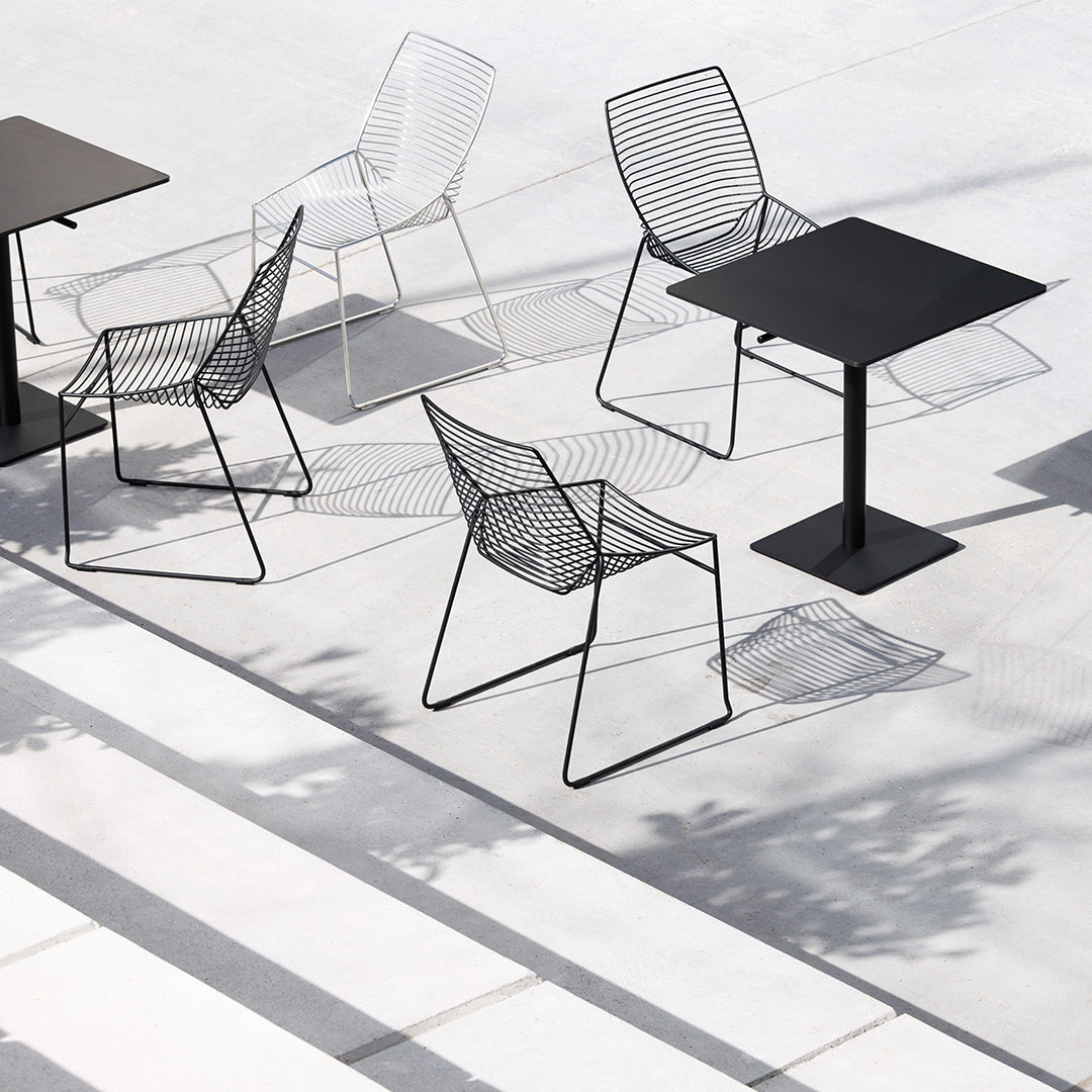 Modern outdoor seating featuring black and white wireframe chairs with geometric patterns on a minimalist patio.