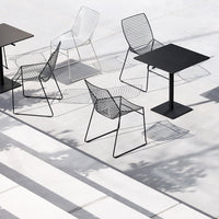 Modern outdoor seating featuring black and white wireframe chairs with geometric patterns on a minimalist patio.