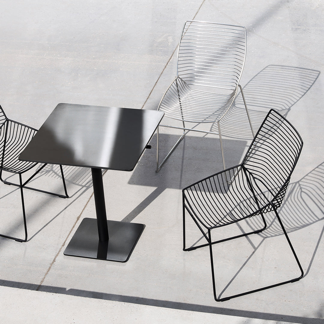 Stylish black metal table with modern wire chairs in sleek, minimalist design and geometric patterns.