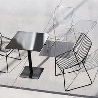 Stylish black metal table with modern wire chairs in sleek, minimalist design and geometric patterns.