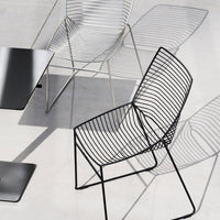 "Modern wire chairs in black and silver with sleek lines and minimalist design on a light gray surface."
