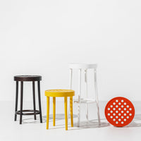 Colorful stools in black, white, yellow, and red with a polka dot pattern on the round seat. Perfect for modern decor.