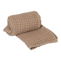 Soft beige waffle weave blanket, showcasing a textured grid pattern with rolled edge detail. Ideal for cozy decor.