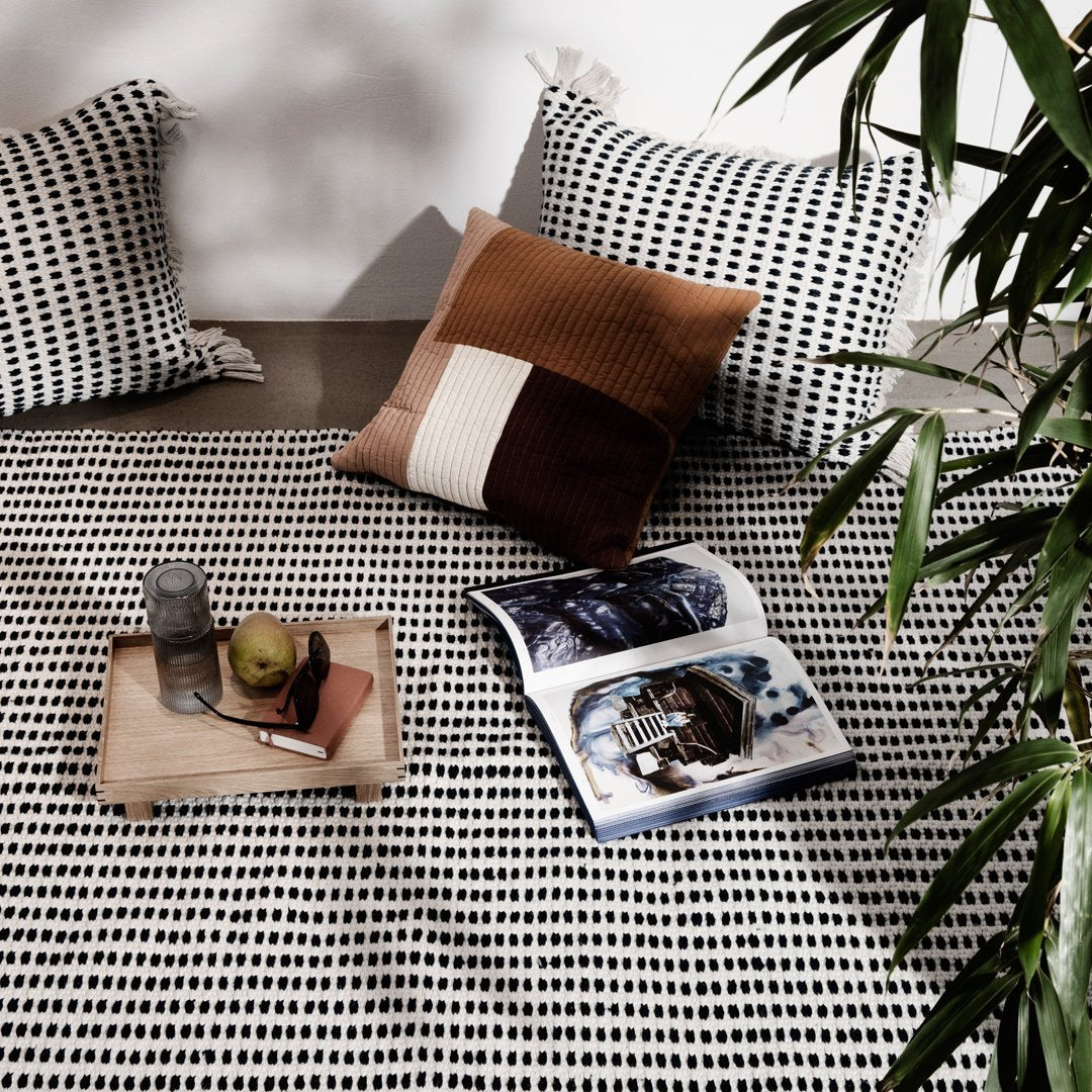 "Black and white patterned fabric with textured brown and cream accent pillows, styled on a modern living space."