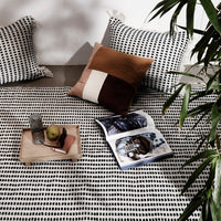 "Black and white patterned fabric with textured brown and cream accent pillows, styled on a modern living space."