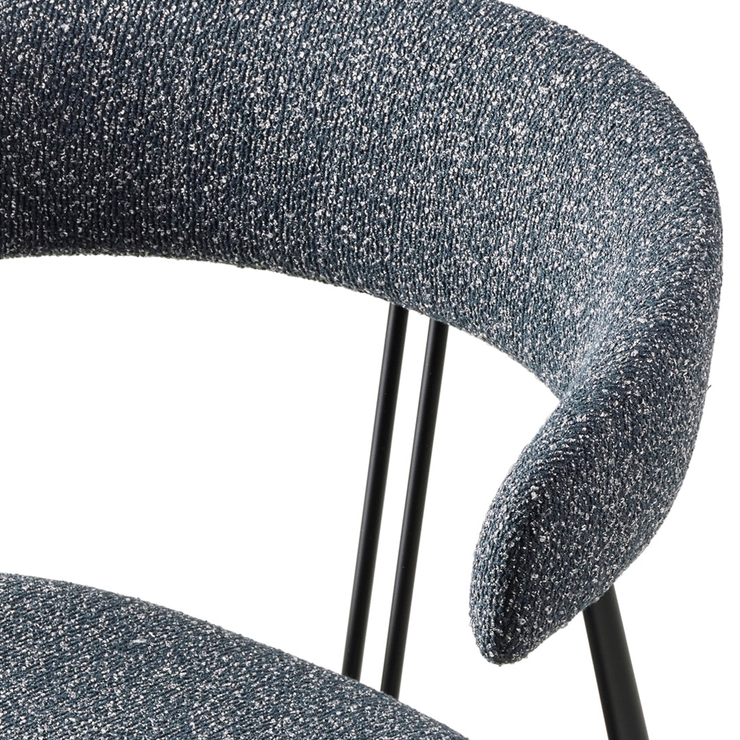 Close-up of a modern chair featuring a speckled blue fabric and sleek black metal legs.