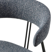 Close-up of a modern chair featuring a speckled blue fabric and sleek black metal legs.