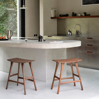 Brown wooden stools with a minimalist design, set against a neutral toned kitchen backdrop. Clean lines and modern aesthetic.