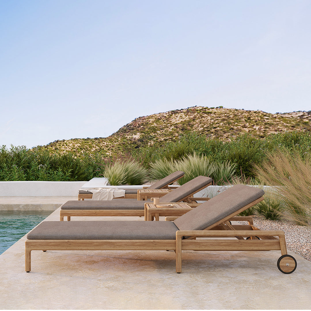 "Neutral-toned lounge chairs with a sleek design against a natural backdrop of greens and earth tones."