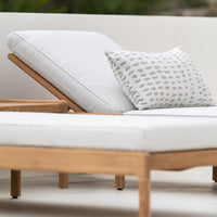 White lounge chair with light wood frame and beige dotted patterned pillow. Neutral tones for a modern aesthetic.