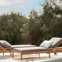 Light grey cushions on natural wood loungers against a serene green backdrop, perfect for outdoor relaxation.