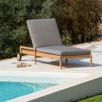 Gray outdoor lounge chair with sleek lines, set against a poolside backdrop and surrounded by greenery.