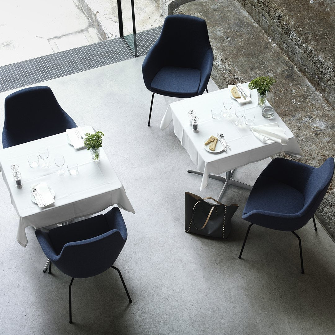 Modern navy blue chairs with white tables, featuring minimalistic design and greenery accents in a chic setting.