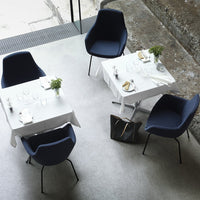 Modern navy blue chairs with white tables, featuring minimalistic design and greenery accents in a chic setting.