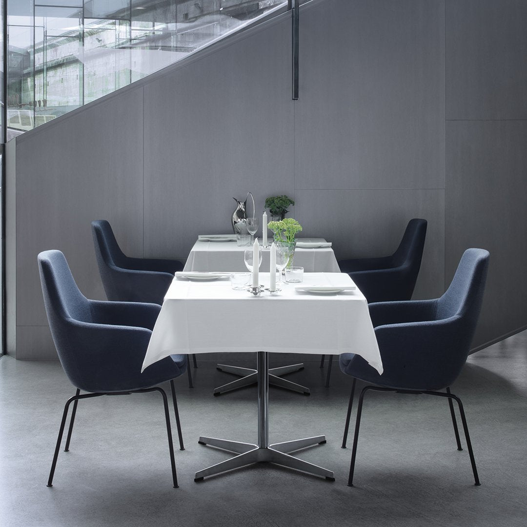 Elegant navy chairs around a white table, set against a modern grey interior for a sleek dining atmosphere.