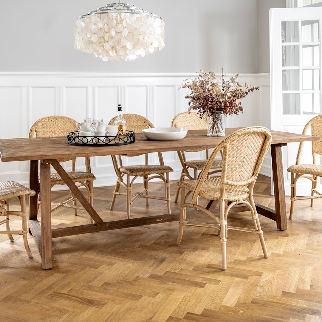 "Light wood dining table with rattan chairs and a stylish chandelier, featuring neutral tones and natural textures."