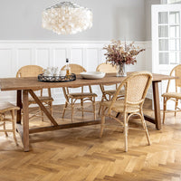 "Light wood dining table with rattan chairs and a stylish chandelier, featuring neutral tones and natural textures."