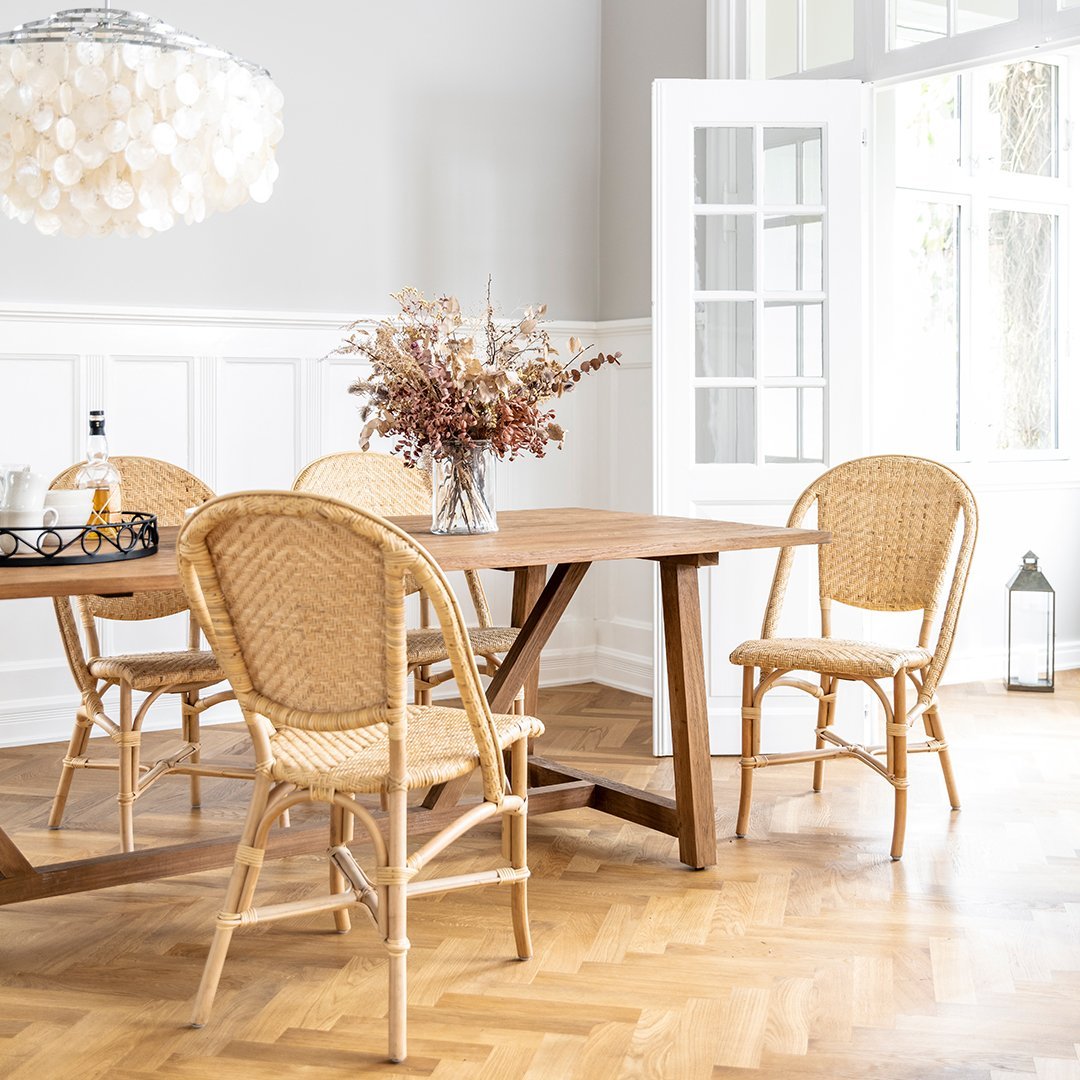 "Natural rattan chairs in a warm wood dining room with a subtle light fixture and neutral decor."