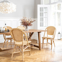 "Natural rattan chairs in a warm wood dining room with a subtle light fixture and neutral decor."