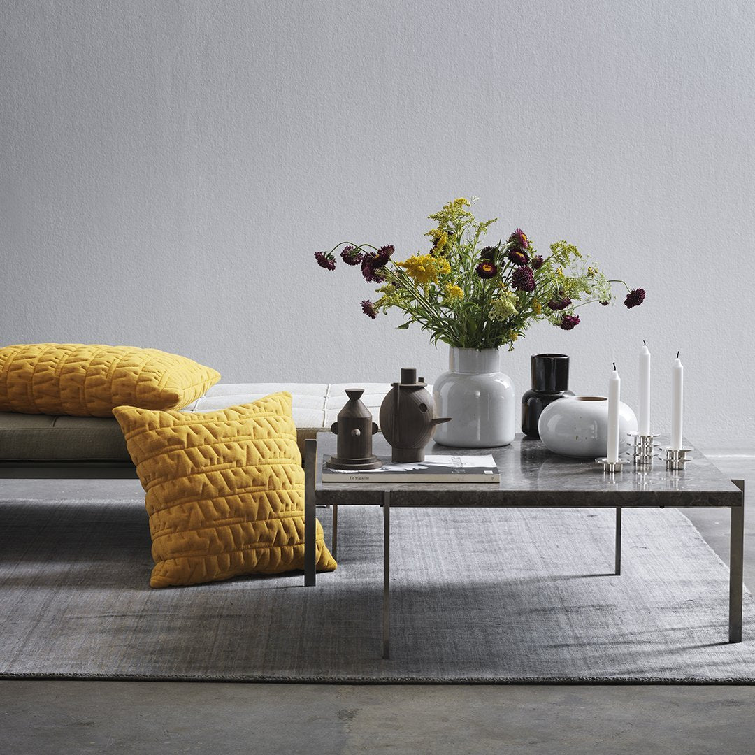 Yellow textured cushions on a neutral couch, with a vibrant flower arrangement and minimalist decor in soft tones.