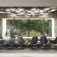 Glass conference room with gray chairs, a textured ceiling, and lush green foliage visible through large windows.