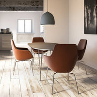 Rustic wooden floor with a modern round table, complemented by brown chairs and a gray pendant light. Simple and stylish.