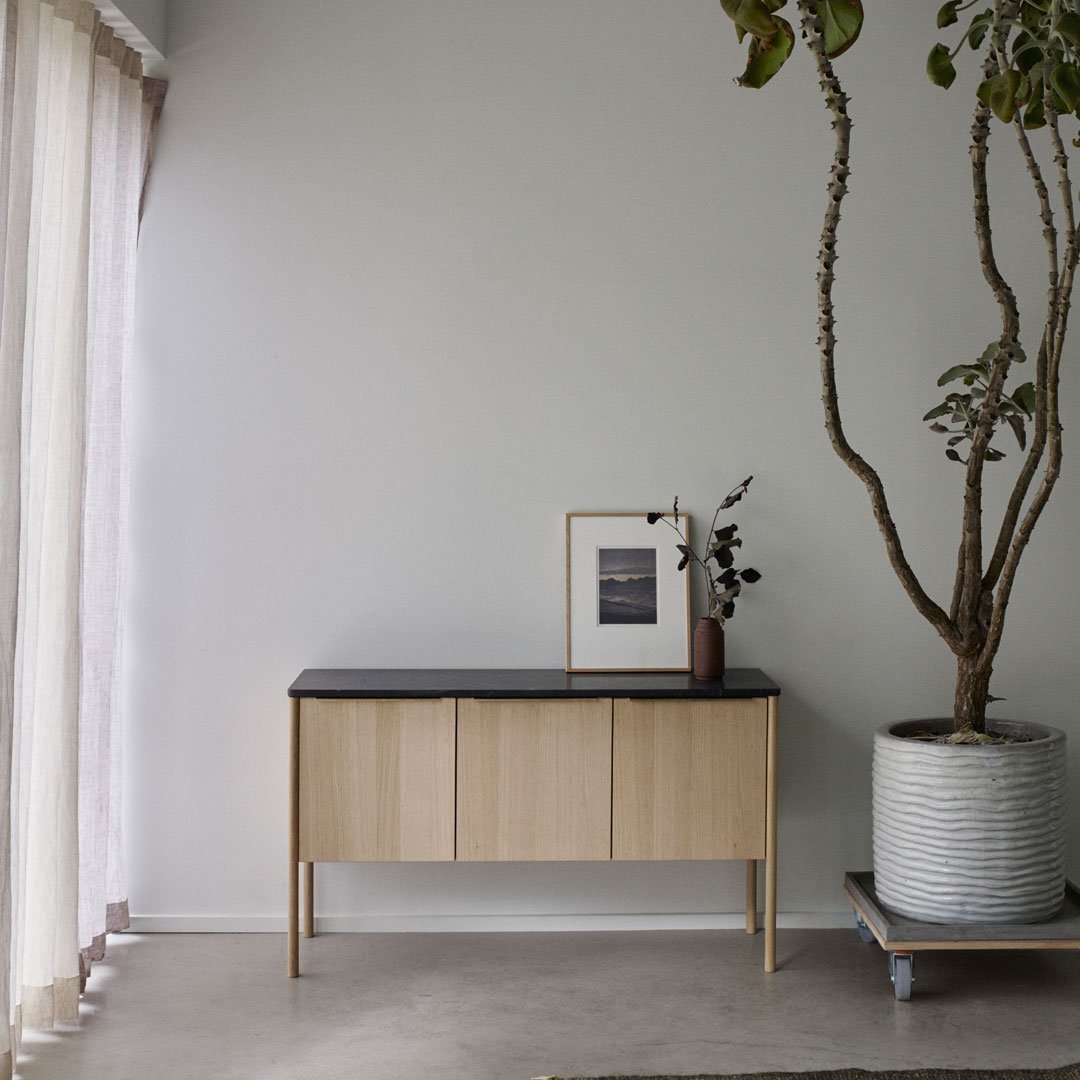Light wood cabinet with a sleek black top, minimal design and a natural, neutral color palette. Ideal for modern decor.