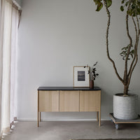 Light wood cabinet with a sleek black top, minimal design and a natural, neutral color palette. Ideal for modern decor.
