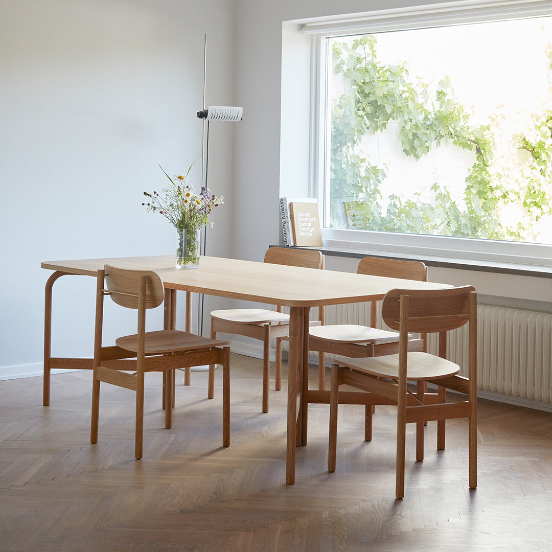 Light wood dining table with natural finish, paired with simple wooden chairs in a clean, minimalist design.