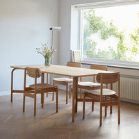 Light wood dining table with natural finish, paired with simple wooden chairs in a clean, minimalist design.