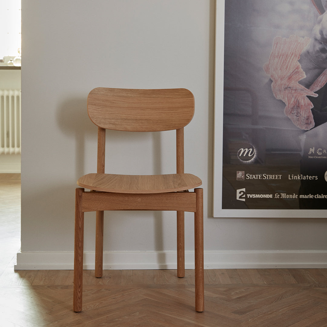 Light natural wood chair with smooth, minimalist design, featuring a soft, curved backrest and a simple, modern aesthetic.