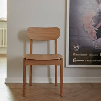 Light natural wood chair with smooth, minimalist design, featuring a soft, curved backrest and a simple, modern aesthetic.