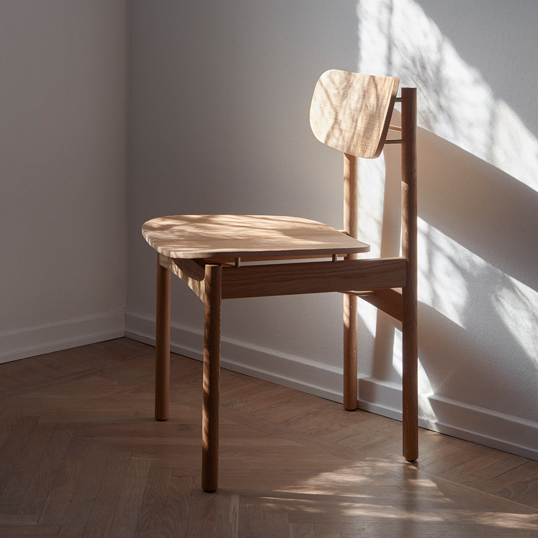 Natural wood chair with light grain patterns, featuring a minimalist design in soft beige tones. Perfect for modern spaces.
