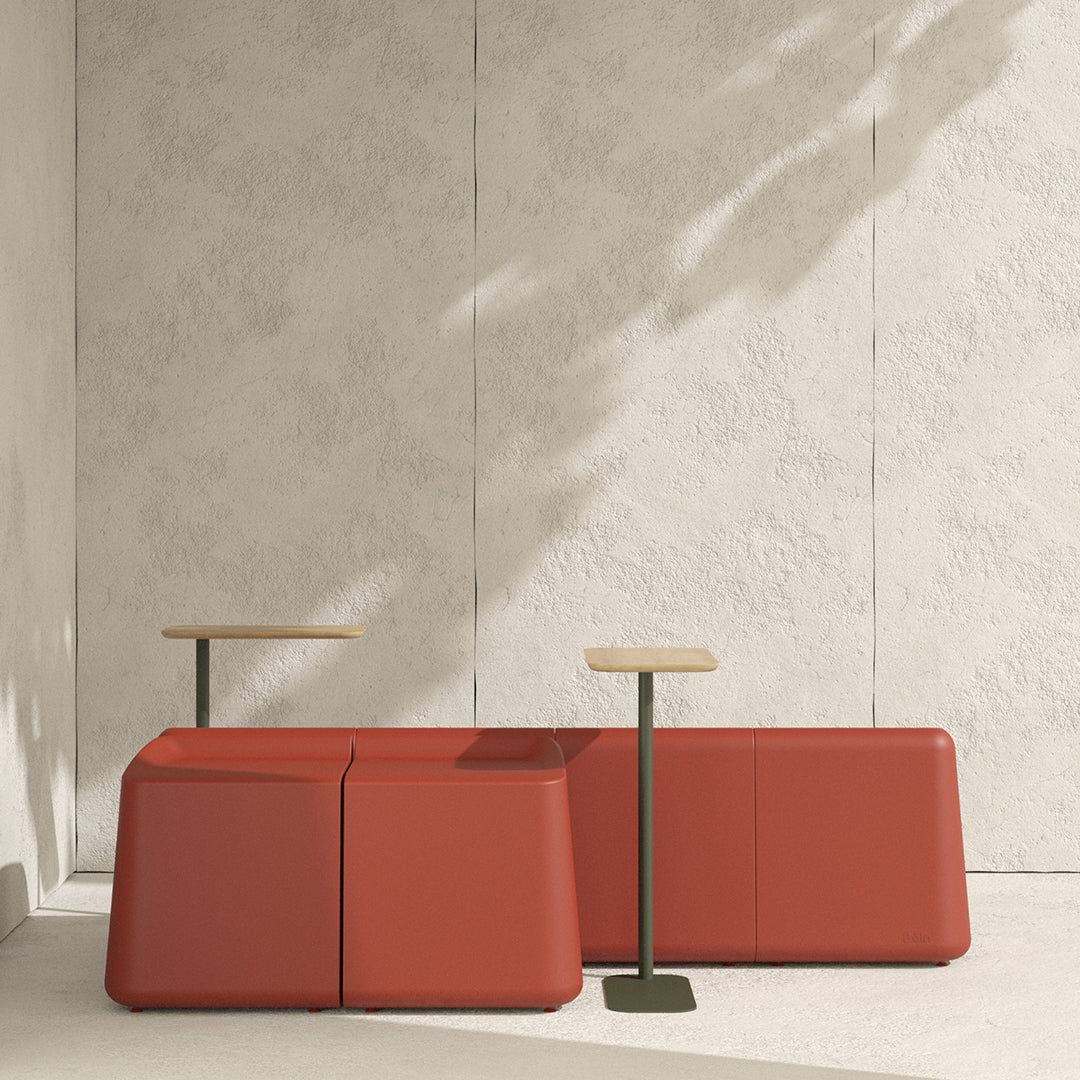 Red modular seating with a smooth texture and minimalist wooden tabletops against a neutral backdrop.