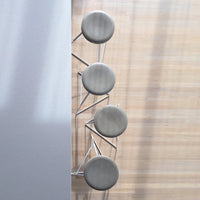 Set of four round gray stools with sleek silver legs against a light wooden background. Modern and stylish design.