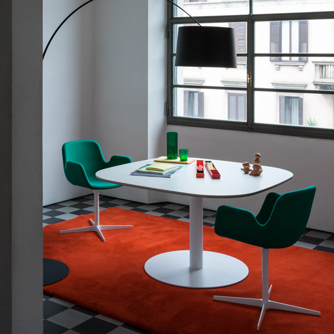Contemporary dining set with white oval table, green chairs, and an orange rug on a black and white tiled floor.