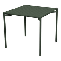 "Square outdoor table in dark green with a textured, slatted surface and sleek, minimal legs."