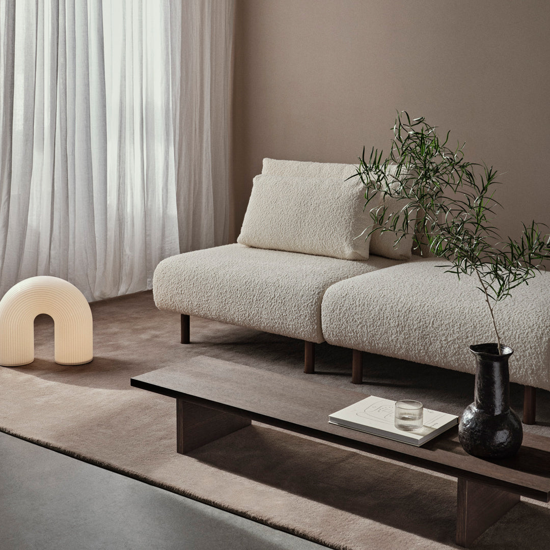 Textured off-white sofa with earthy tones and soft, neutral patterns in a modern living space.