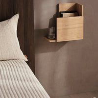 Natural wood nightstand with a light beige fabric bedspread and subtle vertical stripes, paired with a minimalist design.
