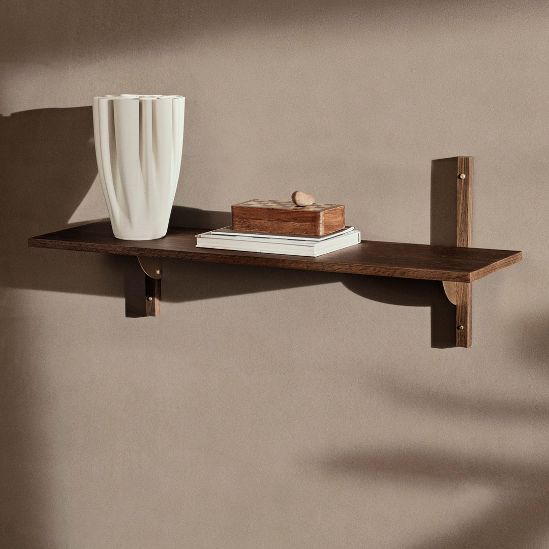 Brown wooden shelf with a smooth finish, featuring a white vase and neutral-colored decor against a beige wall.