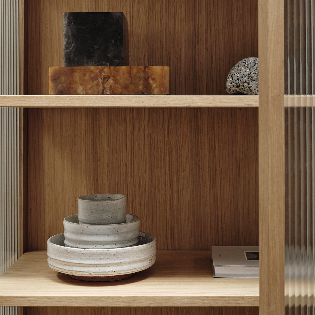 "Neutral gray and black stone decor on wooden shelves with warm wood texture and sleek lines."