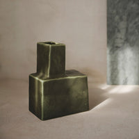 Green abstract-shaped vase with a matte finish, showcasing a unique geometric design against a soft backdrop.