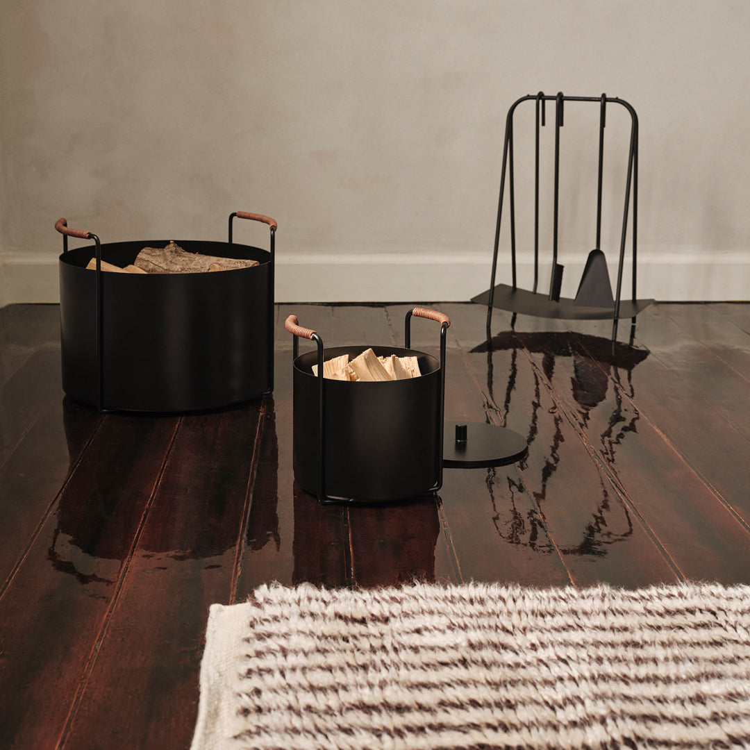 Black metal baskets with copper handles, featuring a sleek, modern design on a dark polished wood floor with a striped rug.