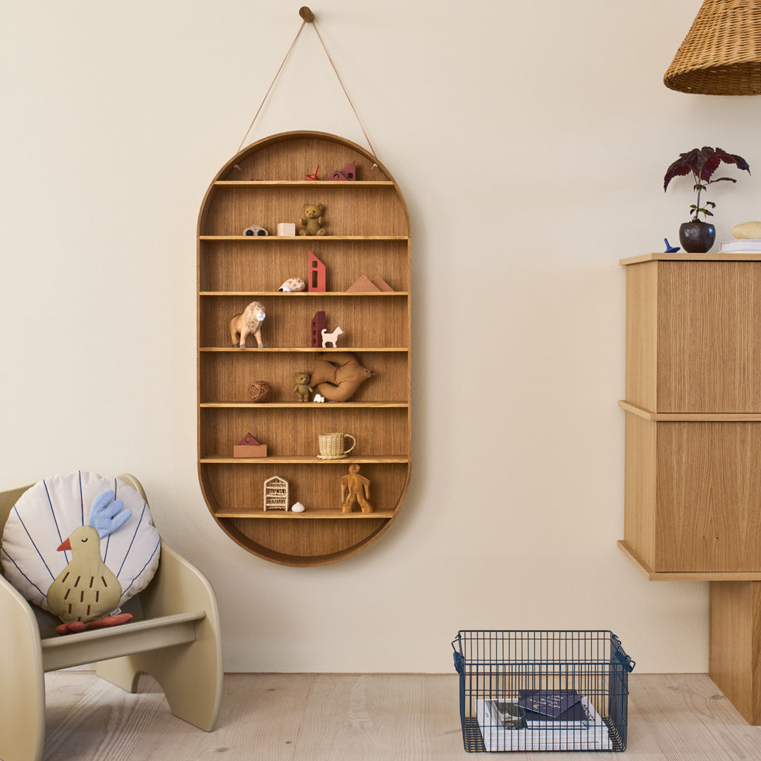 Wooden wall shelf with an oval shape, featuring natural tones and playful decor items against a cream-colored wall.