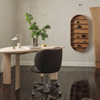 Dark brown office chair with a sleek design, light wood desk, and natural wood shelf in a neutral-toned room.