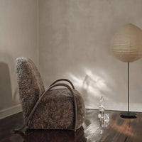 Textured brown chair with curved wooden arms, complemented by a neutral setting and soft, warm lighting.
