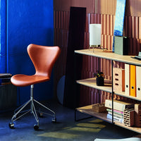 Brown swivel chair against a blue wall and patterned wood paneling, with stylish shelving displaying office supplies.