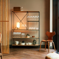Black metal frame open shelving with wood accents, featuring clear glassware and neutral ceramic dishware.