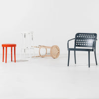 Colorful furniture set featuring a red stool, white chair, natural wood piece, and navy patterned armchair.