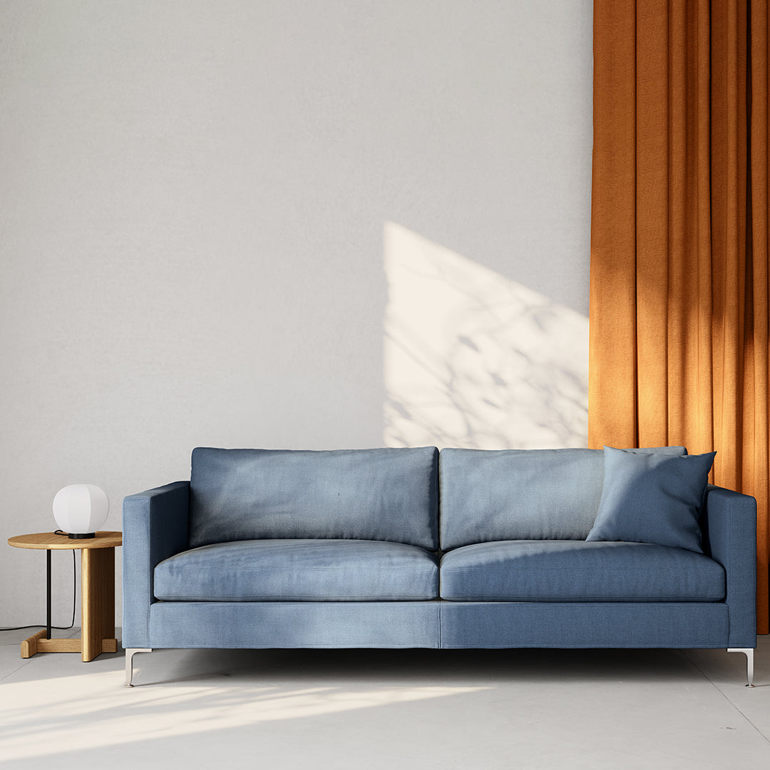 Blue fabric sofa with clean lines, paired with warm orange curtains for a modern contrast.